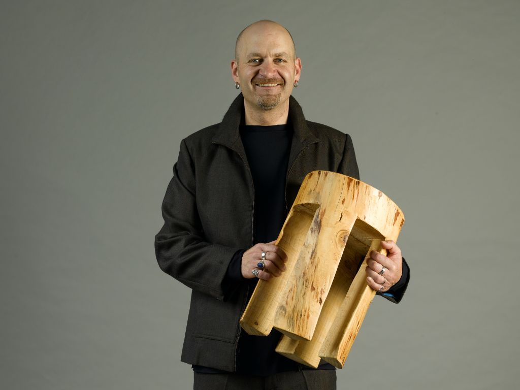 Ralf Klemmer mit Baumstammhocker als Portrait für PRACHTWERK.